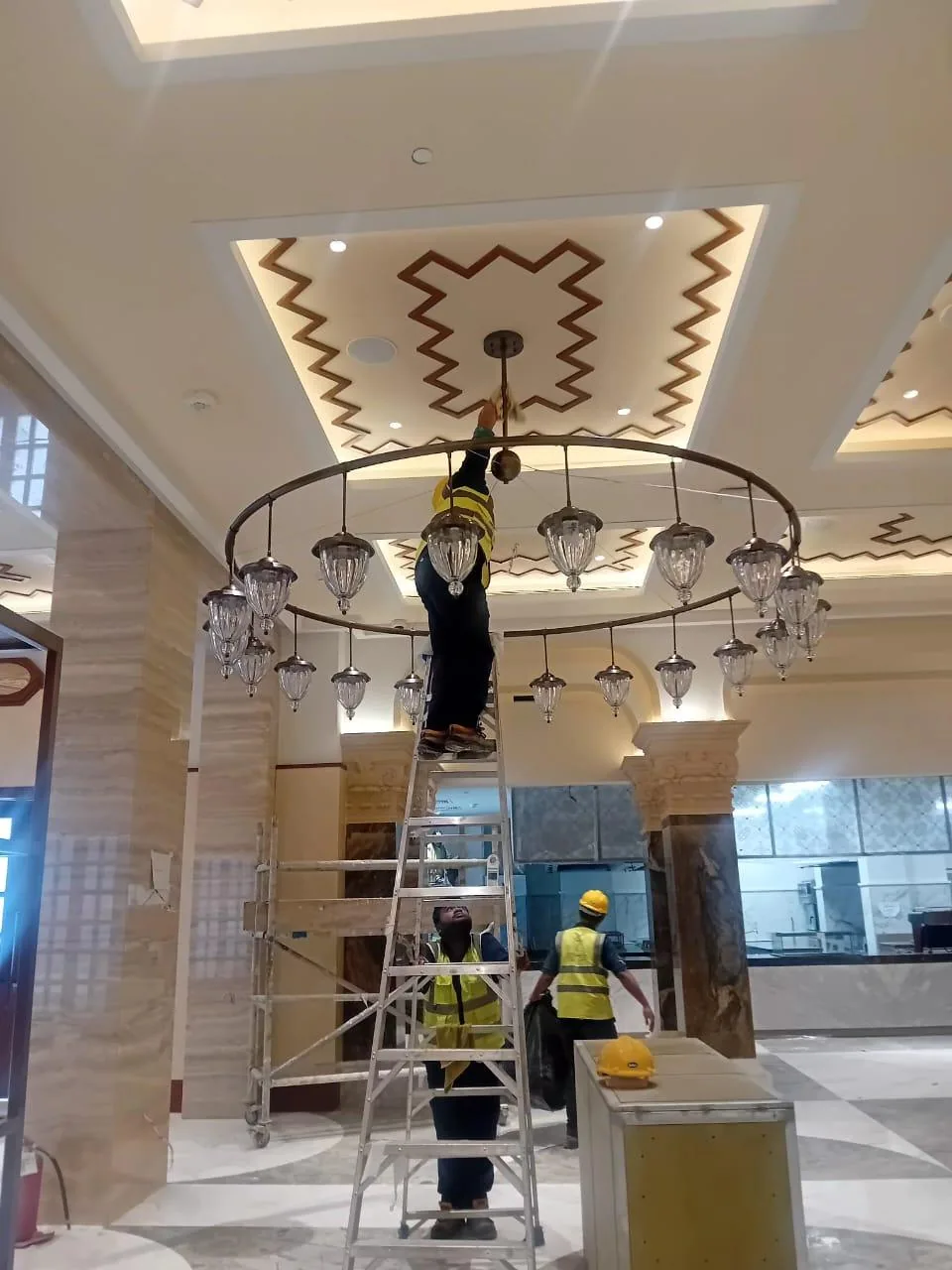 عامل ينظف ثريا كبيرة باستخدام معدات وصول مرتفع