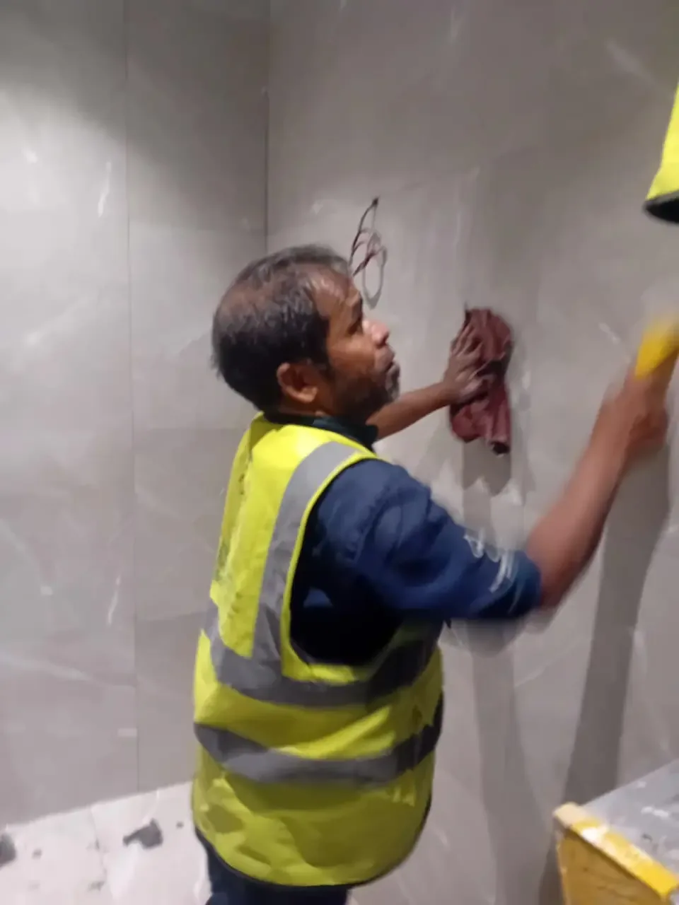 عامل ينظف جدارًا حجريًا أو مبلطًا واسعًا يدويًا