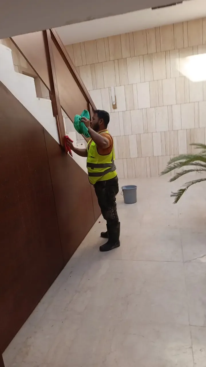 عامل ينظف جدارًا داخليًا مرتفعًا أو ألواح خزائن