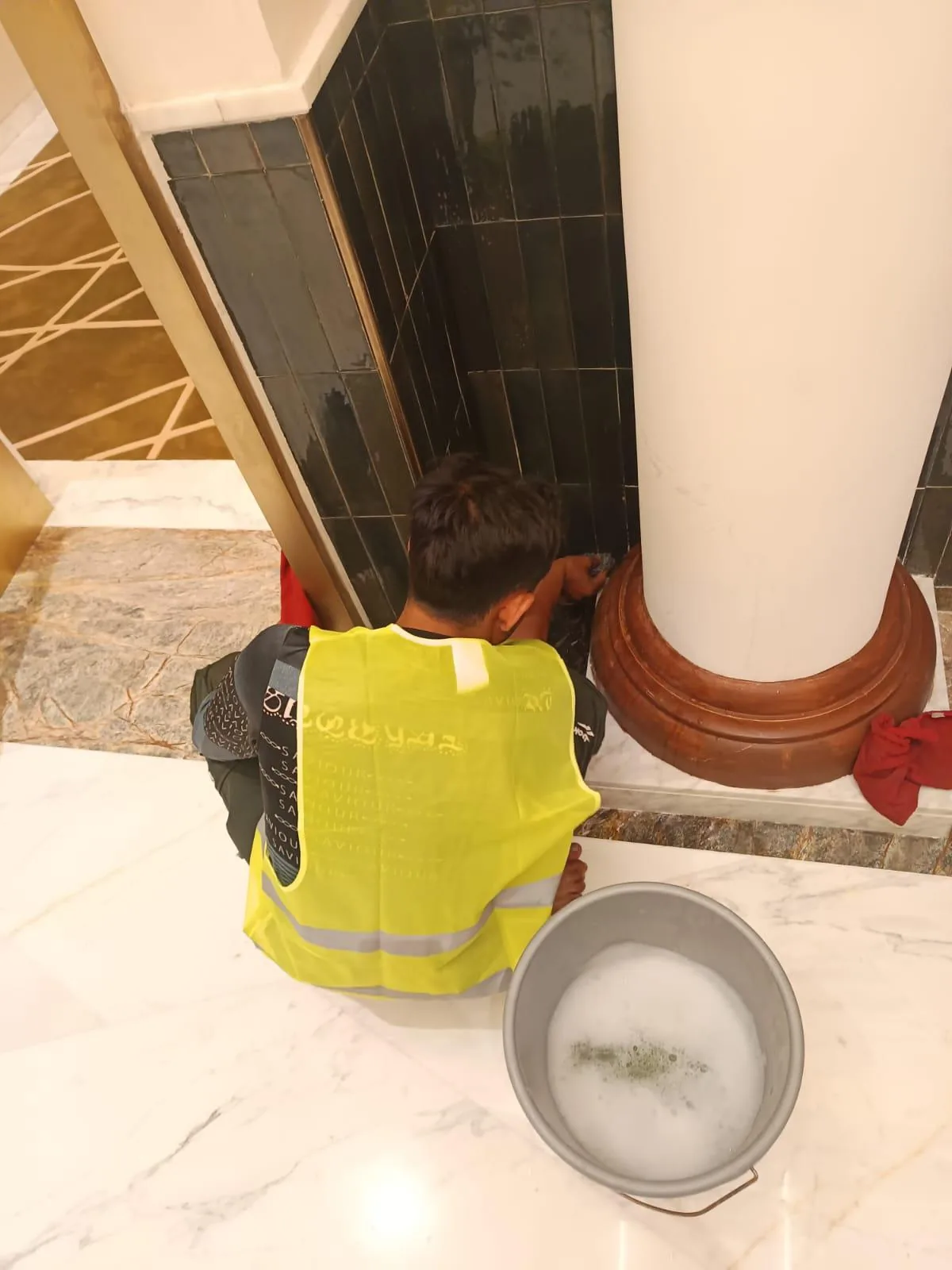 عامل ينظف ألواحًا جدارية وقواعد حائط وأسطحًا زخرفية بالتفصيل