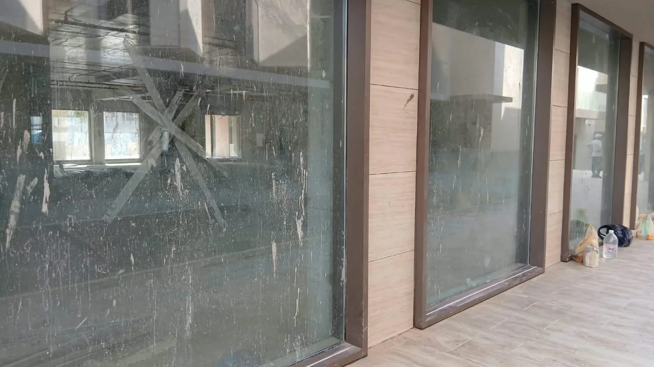 عمال ينظفون واجهة زجاجية مرتفعة بسقالة أو معدات وصول