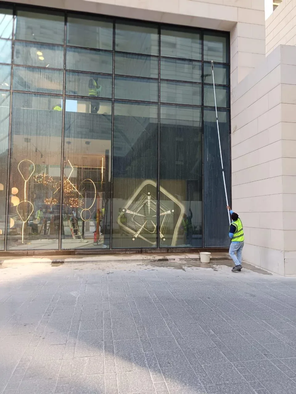 عامل ينظف واجهة زجاجية كبيرة لمحل تجاري