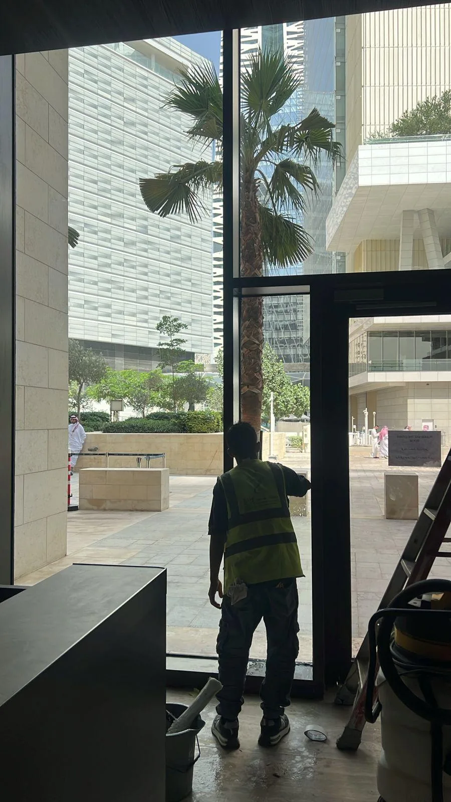 عامل ينظف أبوابًا زجاجية مرتفعة في فيلا
