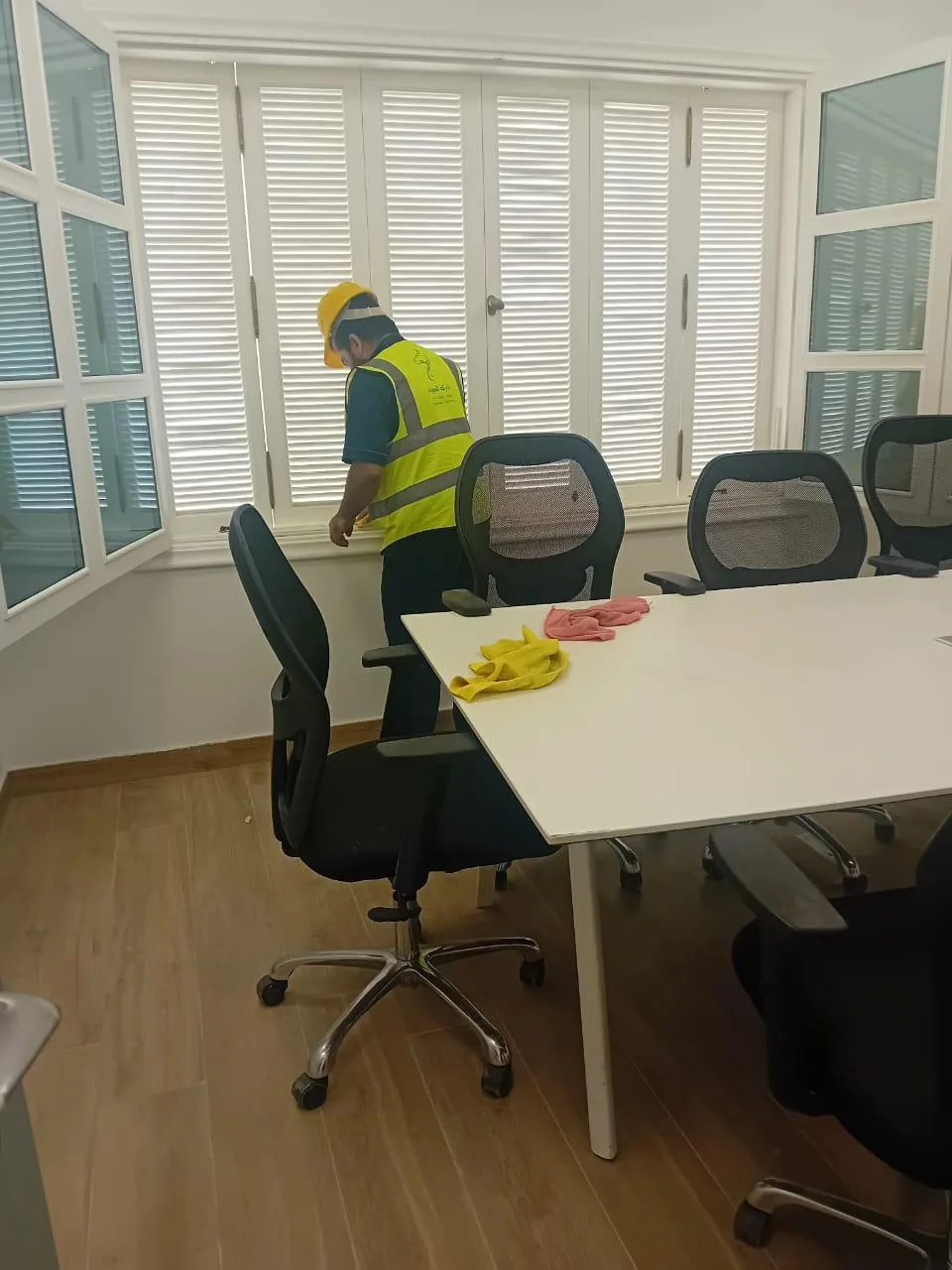 عامل ينظف المكاتب وأسطح محطات العمل داخل مكتب