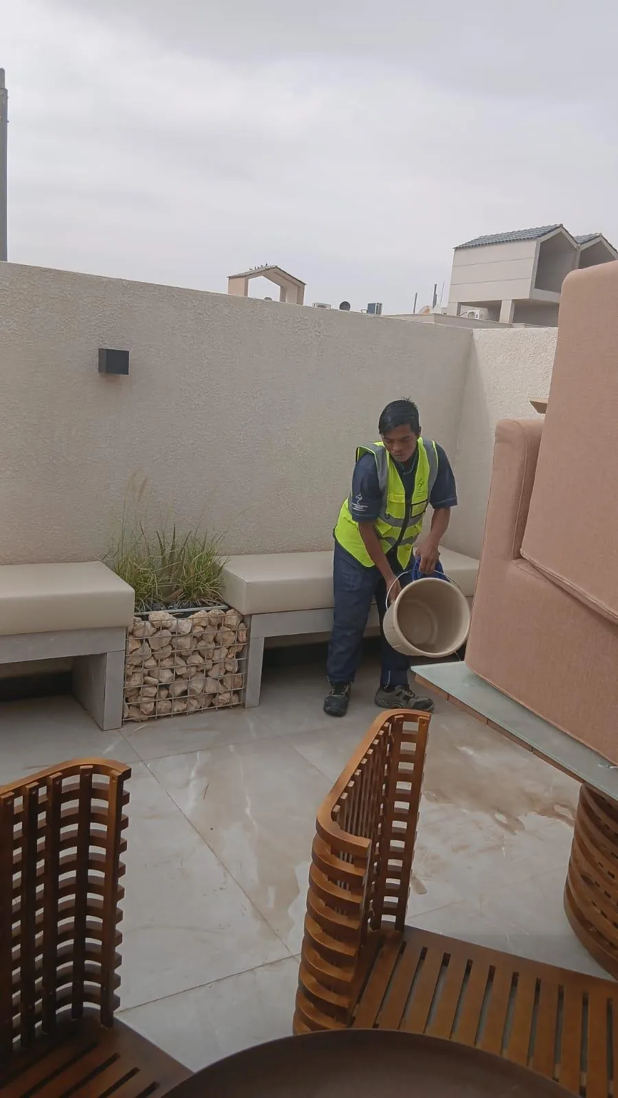 عامل ينظف فناءً خارجيًا وأثاثه في عقار سكني