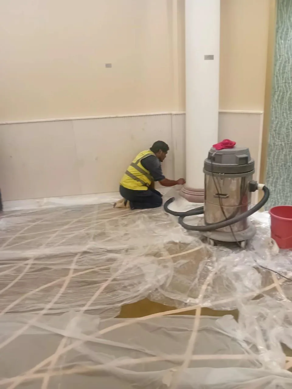 عامل ينظف أرضية داخلية سكنية باستخلاص الأوساخ