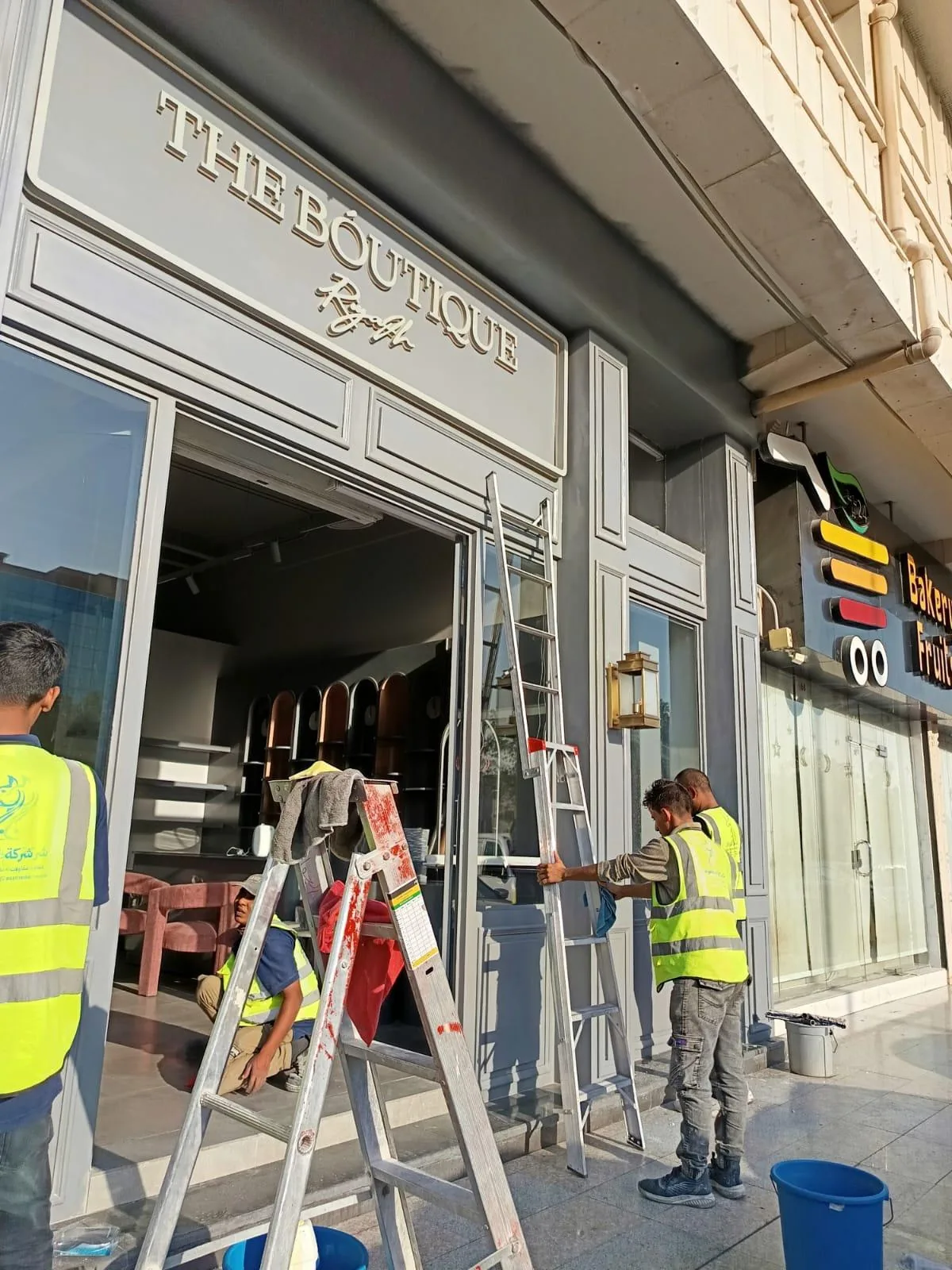 طاقم تنظيف يعمل عند مدخل واجهة محل تجاري